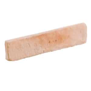 Pieza de mármol beige con textura rugosa, forma rectangular.
