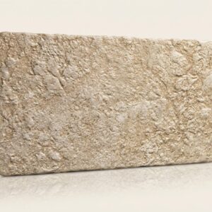 Azulejo rectangular beige con textura rugosa de piedra natural. Es un revestimiento pared exterior.
